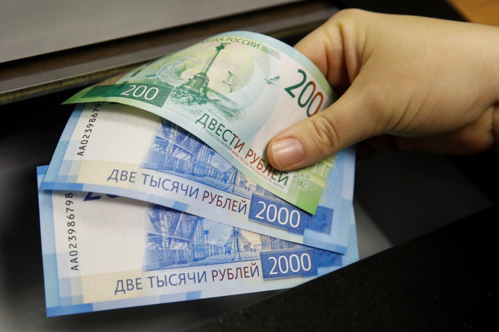 Žena podiže novčanice rublje sa bankomata u Moskvi (Foto: REUTERS/Maxim Shemetov)