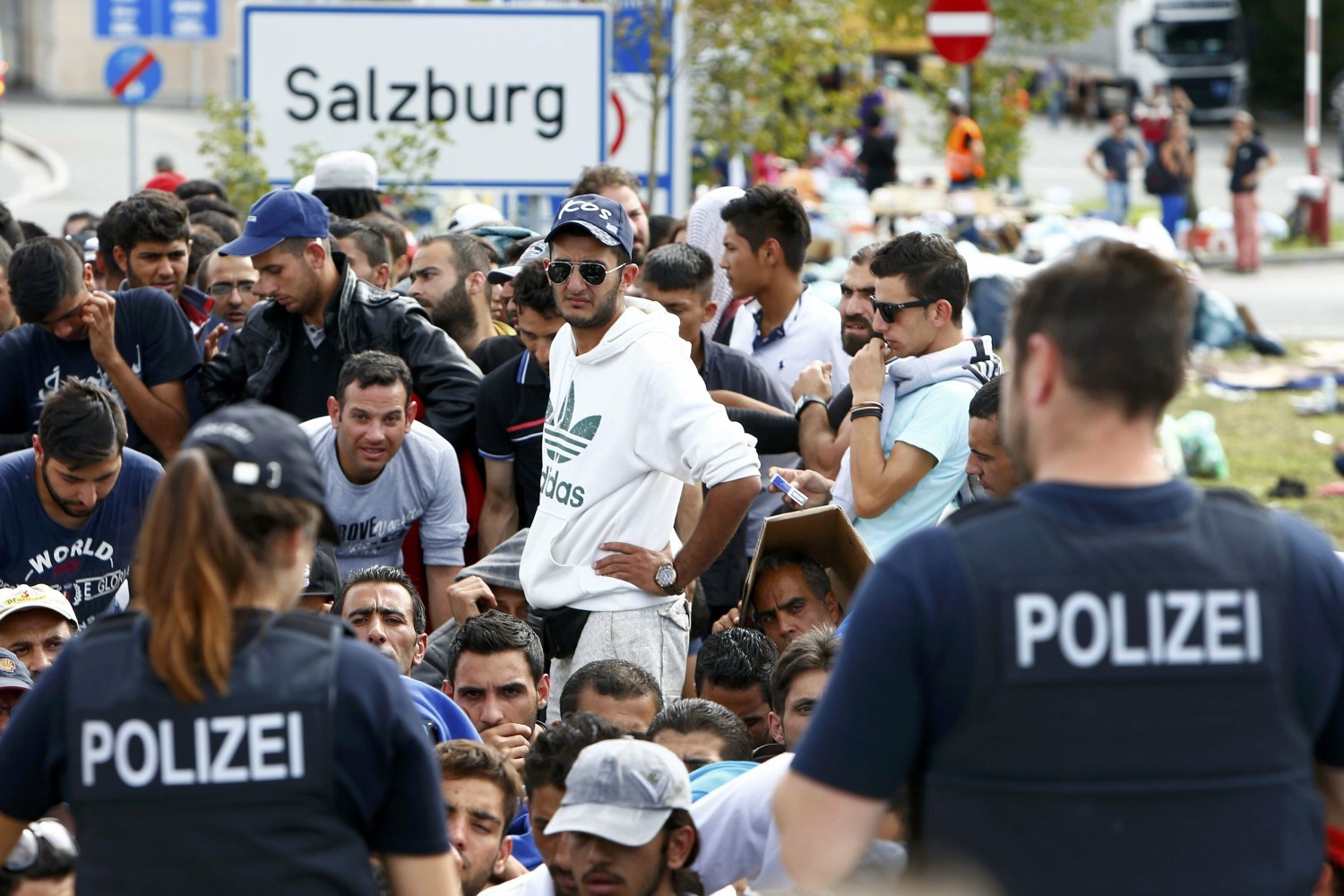 Nemački policajci ispred migranata koji čekaju da pređu granicu između Austrije i Nemačke kod Frajlasinga, 17. septembar 2015. (Foto: Reuters/Michaela Rehle)