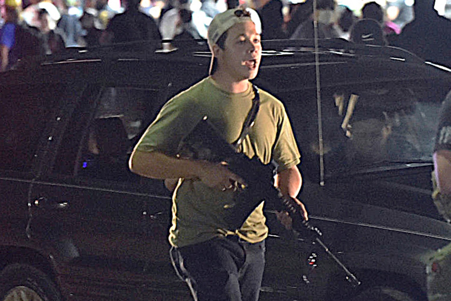 FILE - In this Tuesday, Aug. 25, 2020 file photo, Kyle Rittenhouse carries a weapon as he walks along Sheridan Road in Kenosha, Wis., during a night of unrest following the weekend police shooting of Jacob Blake. Rittenhouse, a 17-year-old accused of killing two protesters days after Jacob Blake was shot by police in Kenosha, Wisconsin, faces a hearing Friday, Sept. 25, 2020 on whether he should be sent to Wisconsin to stand trial on homicide charges that could put him in prison for life. (Adam Rogan/The Journal Times via AP, File)