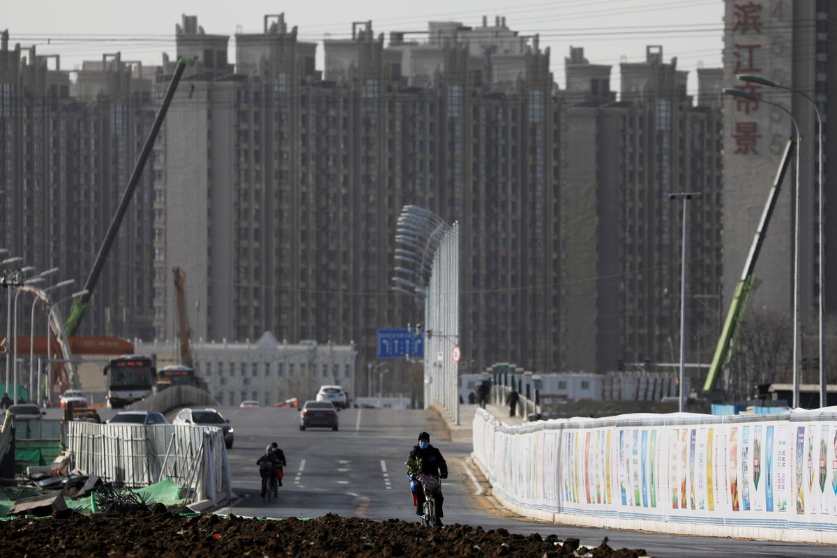 FILE PHOTO:A man rides a bicycle next to a construction site near residential buildings in Beijing, China, January 13, 2021. Picture taken January 13, 2021. Reuters/Tingshu Wang