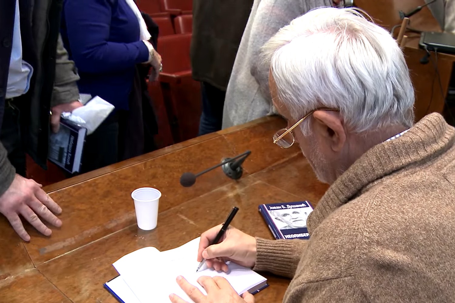 Jovan B. Dušanić tokom potpisivanja svoje knjige „Neoliberalizam“ (Foto: Snimak ekrana/Jutjub/Catena mundi)