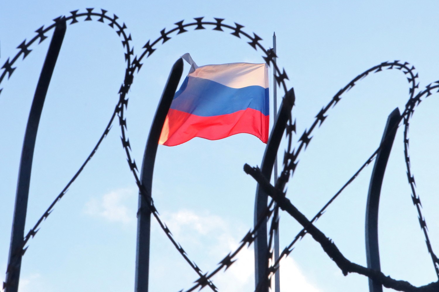 The Russian flag is seen behind a razor wire fence on the roof of the Russian Consulate General in Kharkiv, Ukraine February 23, 2022. Reuters/Vyacheslav Madiyevskyy
